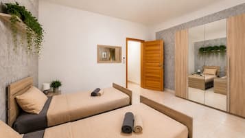 A modern bedroom with two beds, a mirror, and a small plant.