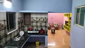 A compact kitchen with a sink, stove, and a small trash bin. - 1BHK Spacious stay near Ramana Ashram in Tiruvannamalai (Tiruvannamalai)