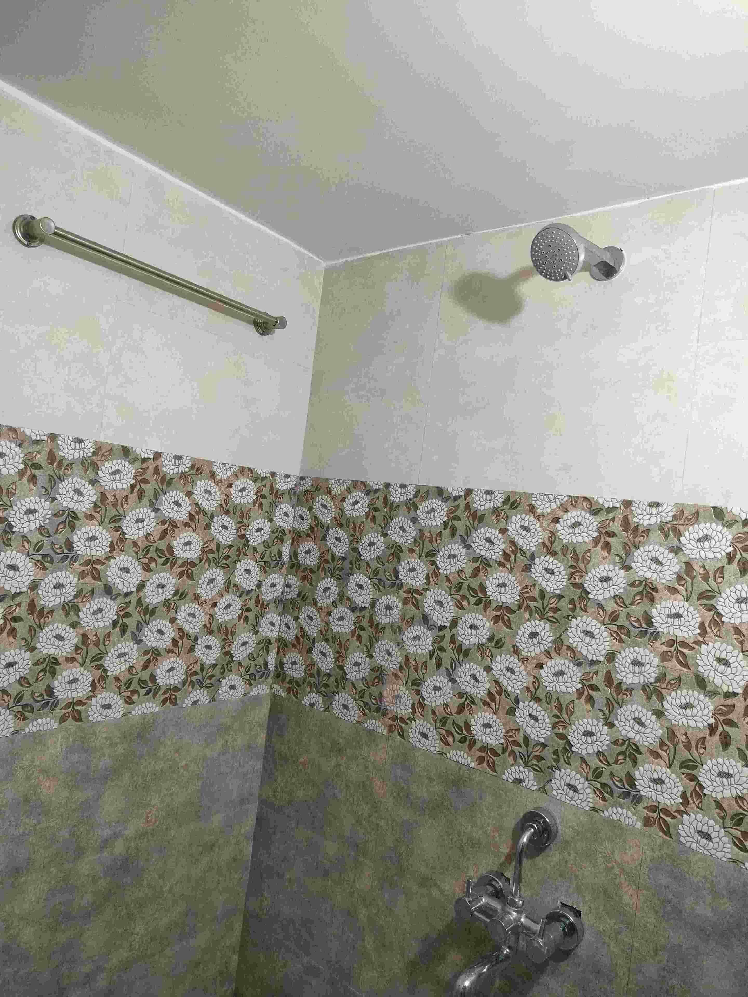 Een badkamer met een douche, een handgreep en een wand met bloemenprint.