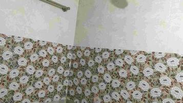 Een badkamer met een douche, een handgreep en een wand met bloemenprint.