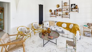 Ein Wohnzimmer mit einer Couch, zwei Sesseln, einem Couchtisch und einer Wandregal mit Dekoration.