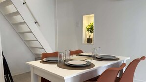 Una mesa de comedor dispuesta con platos, vasos y una planta en maceta.