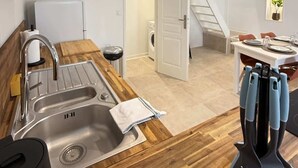 Una cocina moderna con un lavamanos de acero inoxidable, encimera de madera y una zona de comedor con mesa y sillas.