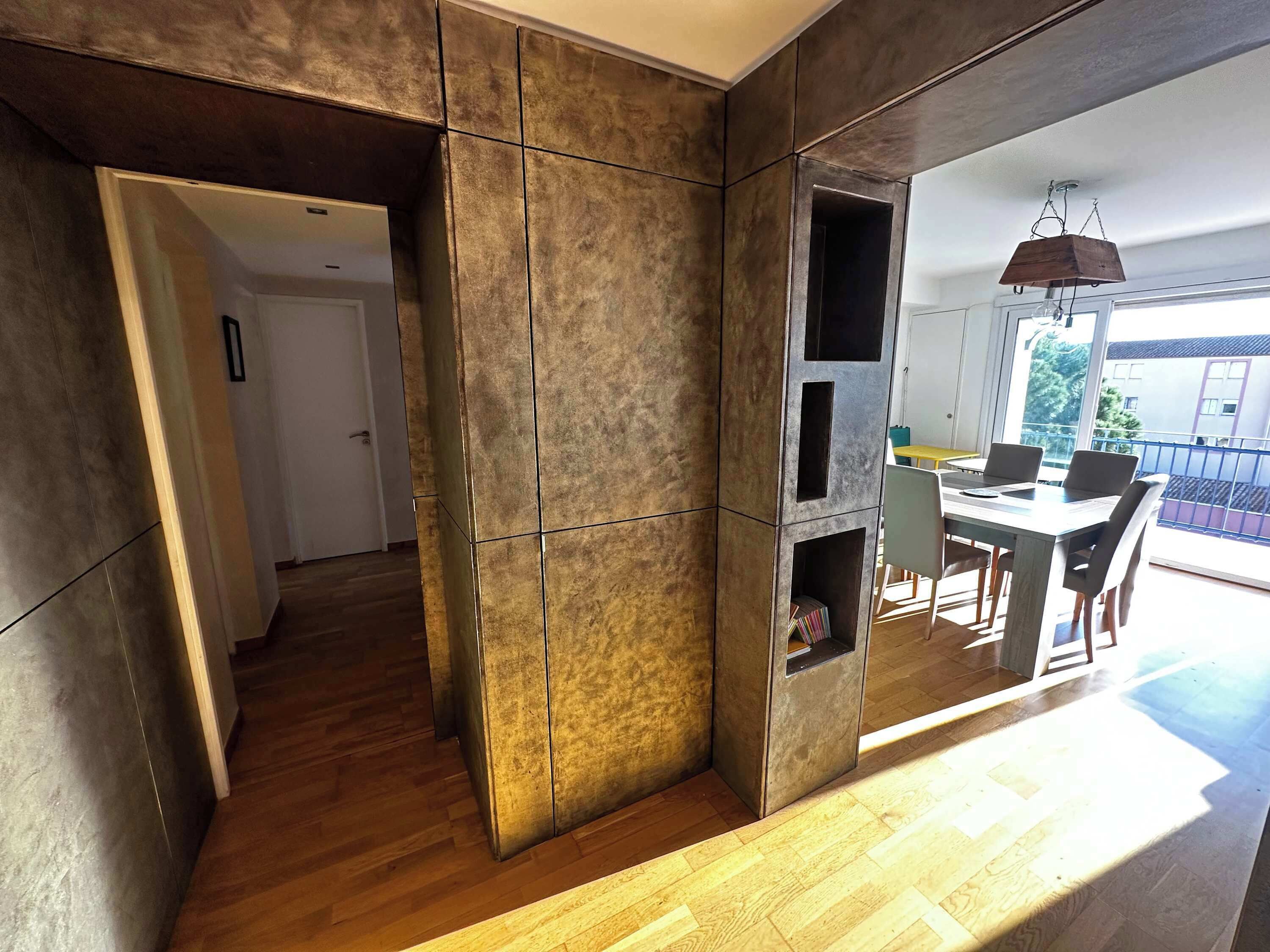A modern interior with a dining area, a view to the outside, and a hallway leading to another room.