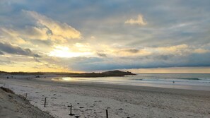 Guests can enjoy a serene beach scene with a wide sandy shore and a distant hill.