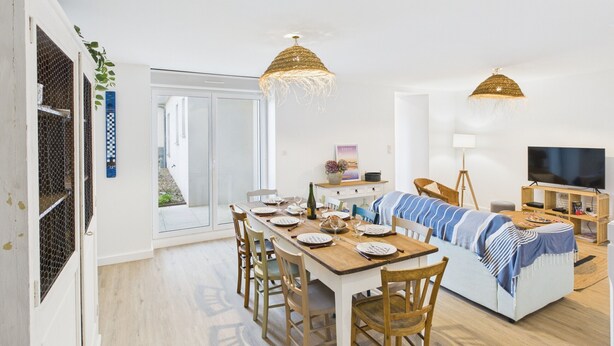 A modern apartment with a dining area, a sofa, and a TV.