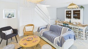 A modern living room with a sofa, a dining table, and a staircase.