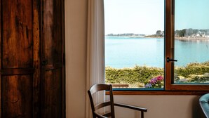 Habitació amb vista a un llac, una cadira de fusta i una finestra que ofereix vistes al llac i al verdor.
