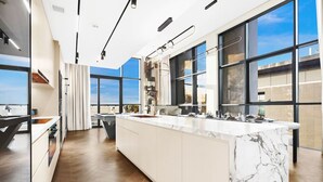 Une cuisine moderne dotée d’un grand îlot central, de grandes fenêtres et offrant une vue sur la ville.