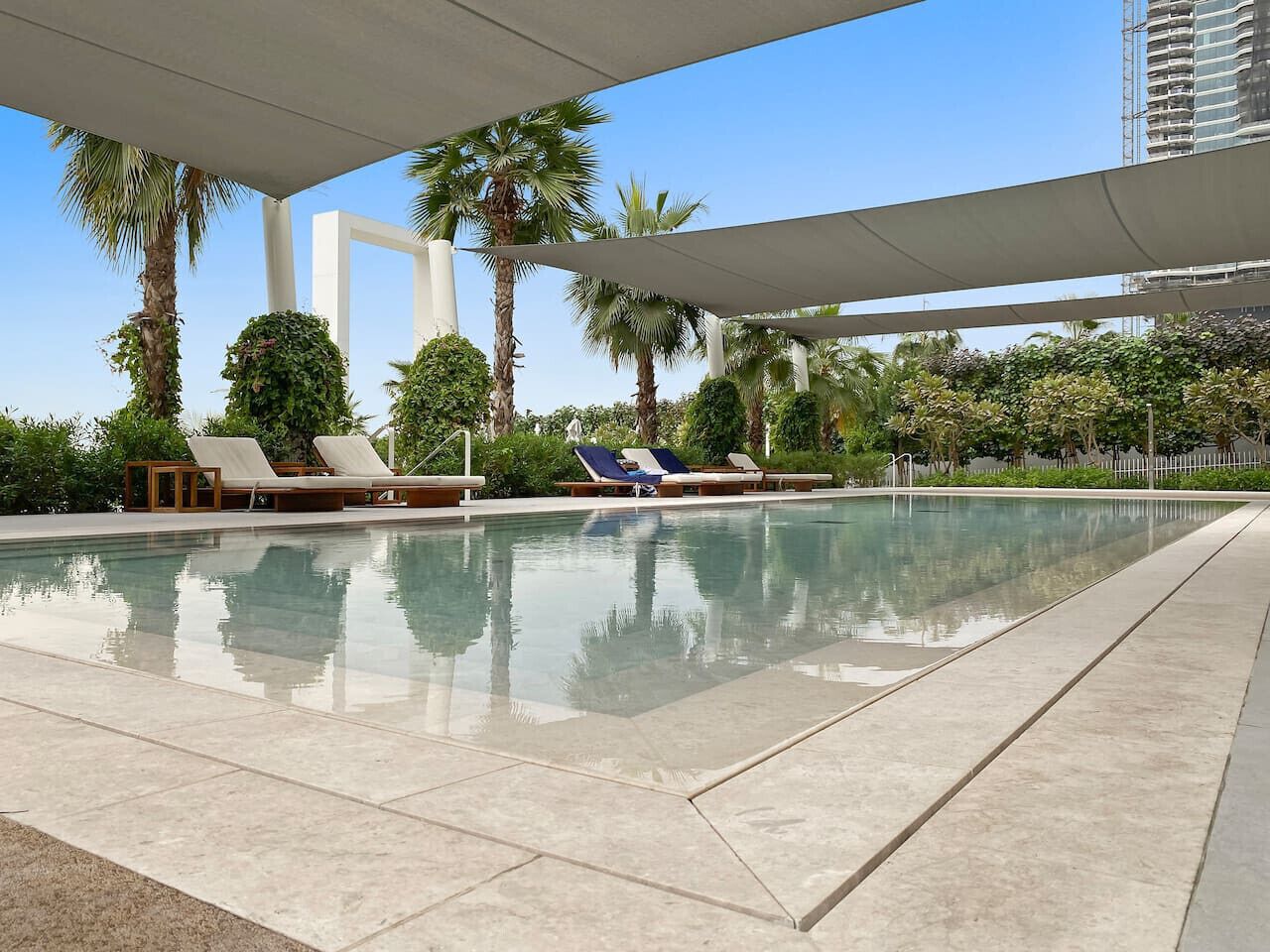 A swimming pool with lounge chairs and palm trees.