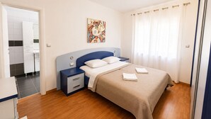 A hotel room with a bed, a nightstand, a painting, and a bathroom visible through an open door. - Holiday Home Nadalina (Vrgorac)