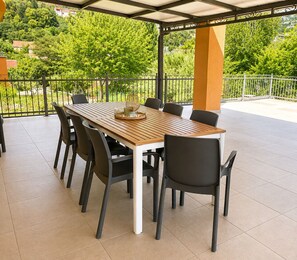 An outdoor patio with a wooden table and chairs, surrounded by a metal railing. - Holiday Home Nadalina (Vrgorac)
