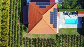 A house with a sloped roof, solar panels, a swimming pool, and a garden.