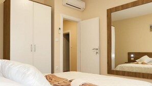 A hotel room with a bed, a wardrobe, a mirror, and an air conditioning unit.