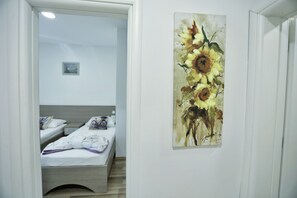 A hotel room with a bed, a painting of sunflowers on the wall, and a small picture on the wall. - Holiday Home Amaya (Vrgorac)