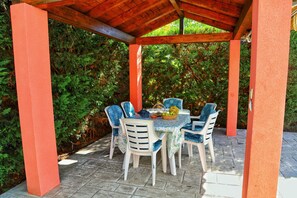 An outdoor patio area with a table and chairs, surrounded by greenery.