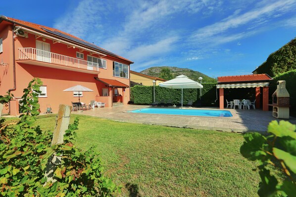 A residential property with a swimming pool, outdoor seating, and a mountain backdrop.