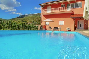 A swimming pool with a view of a mountain and a building with a balcony.