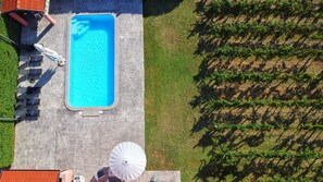 An aerial view of a swimming pool area with a patio, lounge chairs, and a pergola.
