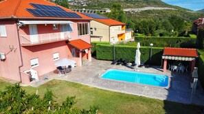 Un immobile residenziale con piscina, pannelli solari e un giardino curato.