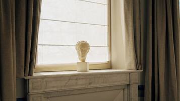 Une cheminée en marbre surmontée d’un buste sculpté, posé sur un piédestal.