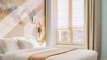 A bedroom with a large bed, a chandelier, a window with curtains, and a patterned wall.