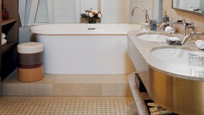Une salle de bain moderne avec un plafond en pente, deux lavabos, une baignoire et un grand miroir.