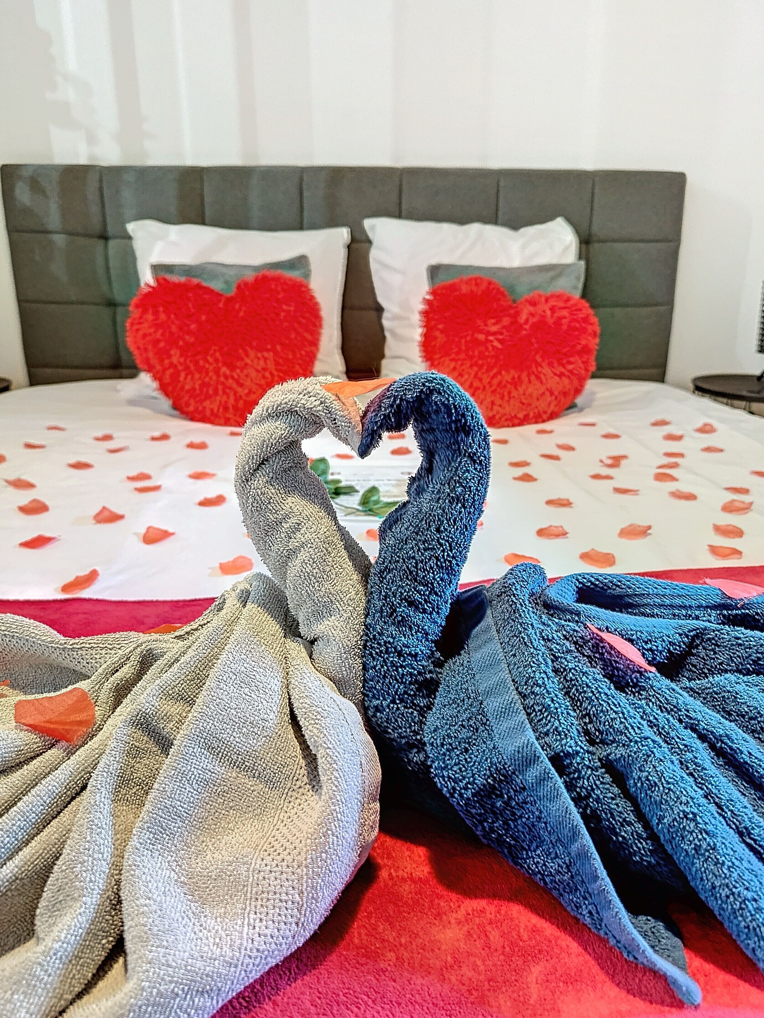 Un lit agrémenté d’un arrangement de coussins en forme de cœur et d’un cygne décoratif fait de serviettes.