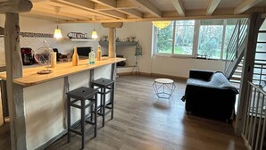 A spacious loft with a kitchen area, a dining space, and a seating area with a view of the outdoors. - Le petit gite dans la prairie (Revel)