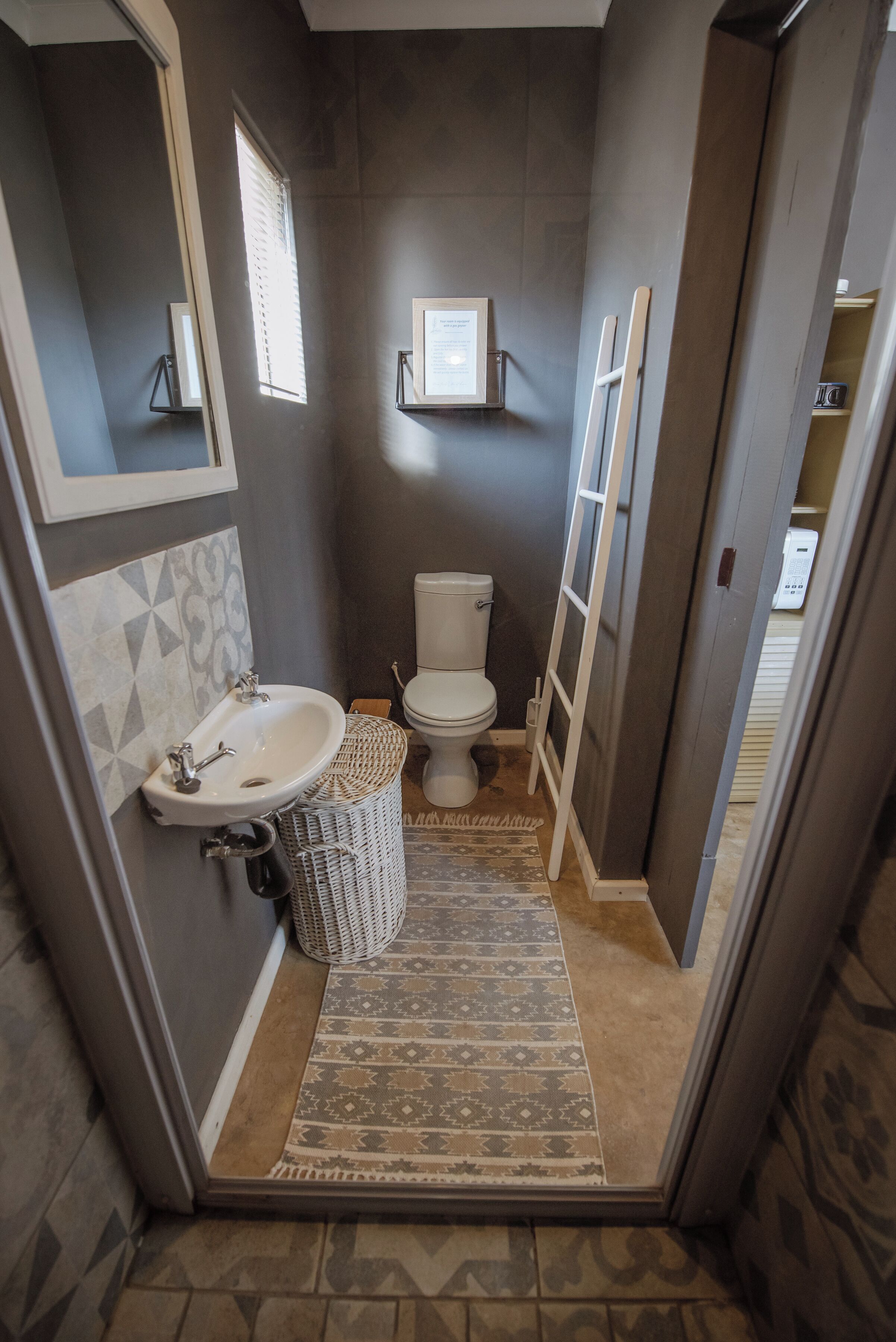 A compact bathroom with a white sink, toilet, and a small window.