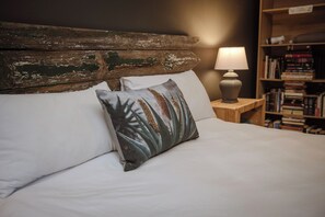 A bed with white linens, a wooden headboard, and a decorative pillow with a nature pattern. - Die Moerbeiboom (Bloemfontein)