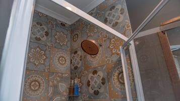 A shower area with patterned tiles and a glass door.
