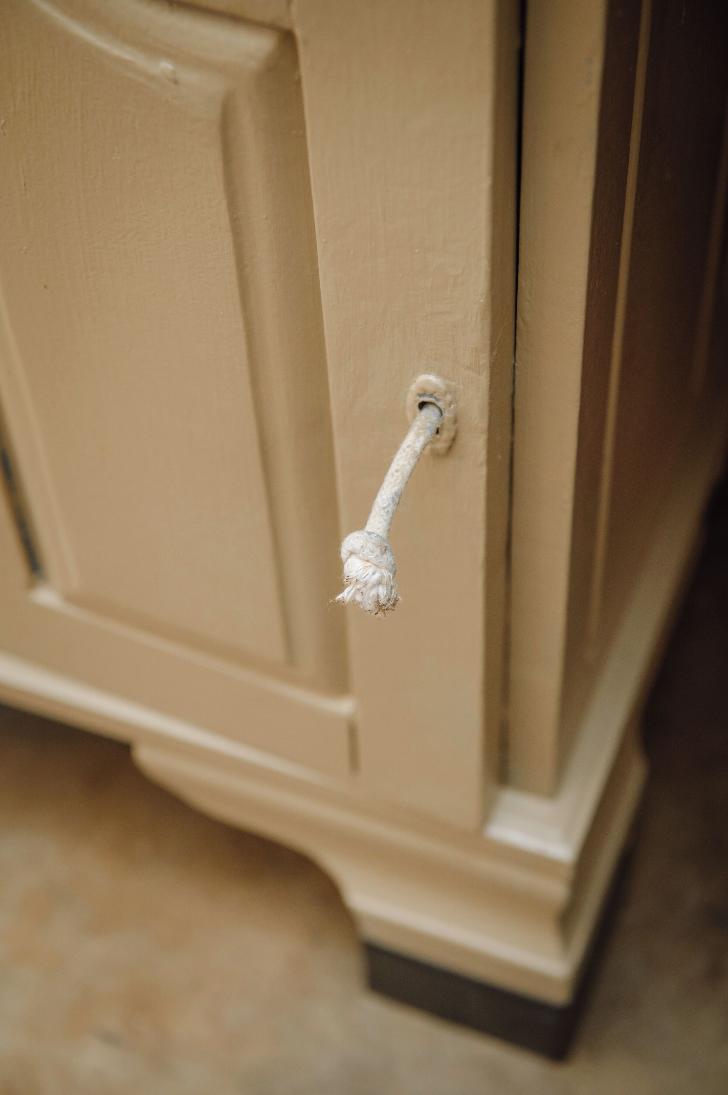 A close-up of a beige door handle with a rope tied to it.