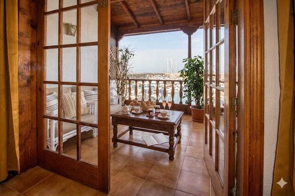A wooden-framed balcony with a table set for breakfast, overlooking a marina.