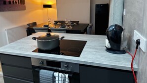 A modern kitchen with a built-in stove, a kettle, and a dining area with a table set for two. - BetaHouse -3BR -Pool Table -Free Parking -Spacious (Greater Manchester)