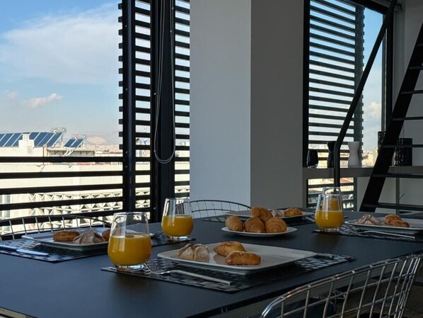A breakfast setup with croissants and orange juice on a table with a city view.