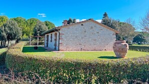 A stone building with a garden and a large vase. - The independent Capannina on the Tuscan hills (Toscana)