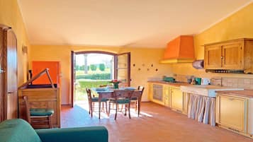 A spacious kitchen with a dining area, a sofa, and a view of the garden.