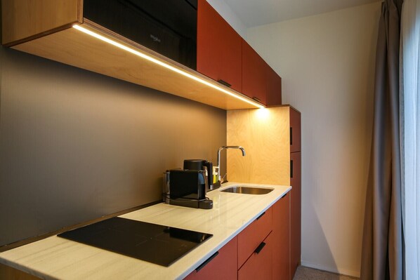 A compact kitchenette with a built-in coffee maker, a sink, and a countertop.