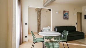 Un salon moderne avec une table ronde blanche, des chaises vertes, un canapé noir et un tableau accroché au mur.