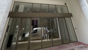 Un bâtiment moderne avec une entrée en verre, de nombreux balcons et un ciel dégagé.