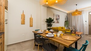 Un coin repas avec une table en bois, des chaises noires et un canapé jaune.