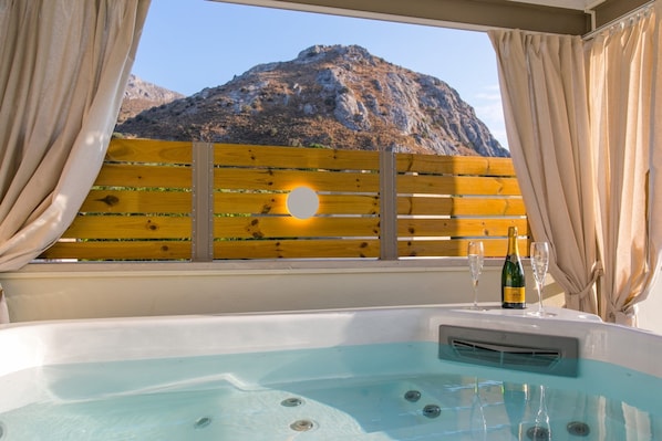 A hot tub with a mountain view, wooden fence, and a bottle of champagne.