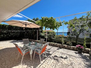 An outdoor patio with a table and chairs, a pergola, and a view of the sea. - Apartman Mona 2 (Dramalj)