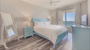 A bedroom with a bed, a nightstand, a dresser, a mirror, and a balcony with a view.