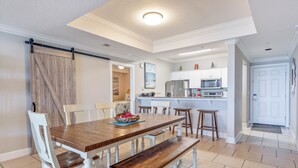 A dining area with a wooden table, white chairs, and a bench.