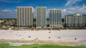 A beachfront hotel with multiple high-rise buildings, a sandy beach, and a clear sky.