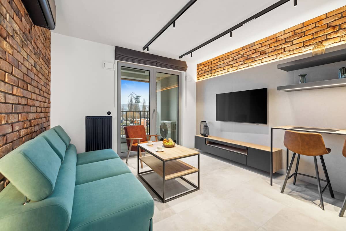 A modern living space with a sofa, a coffee table, a TV, and a brick accent wall.