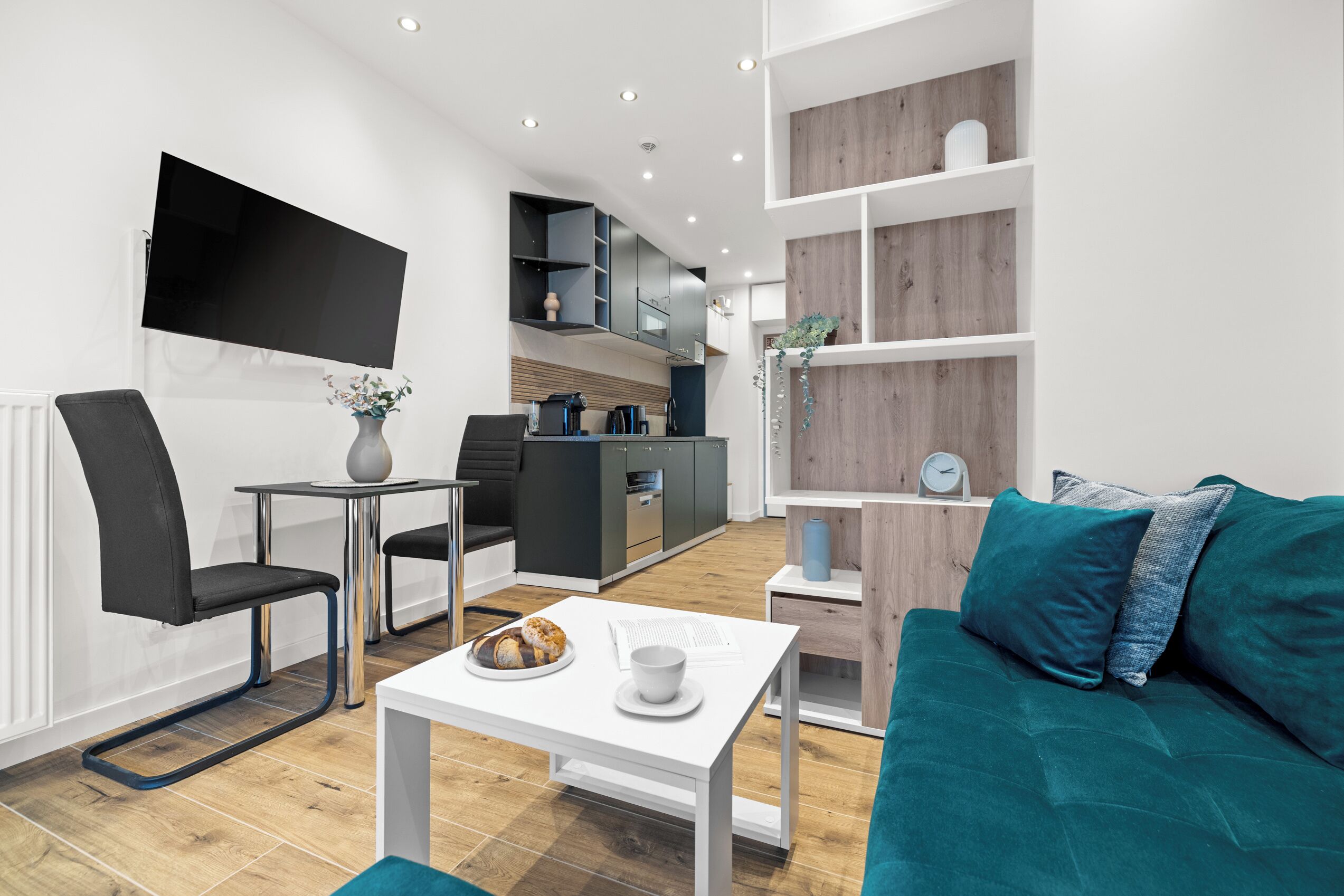 Een moderne woonkamer met een flatscreen televisie, een eethoek en een keuken.
