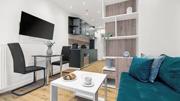 Een moderne woonkamer met een flatscreen televisie, een eethoek en een keuken.